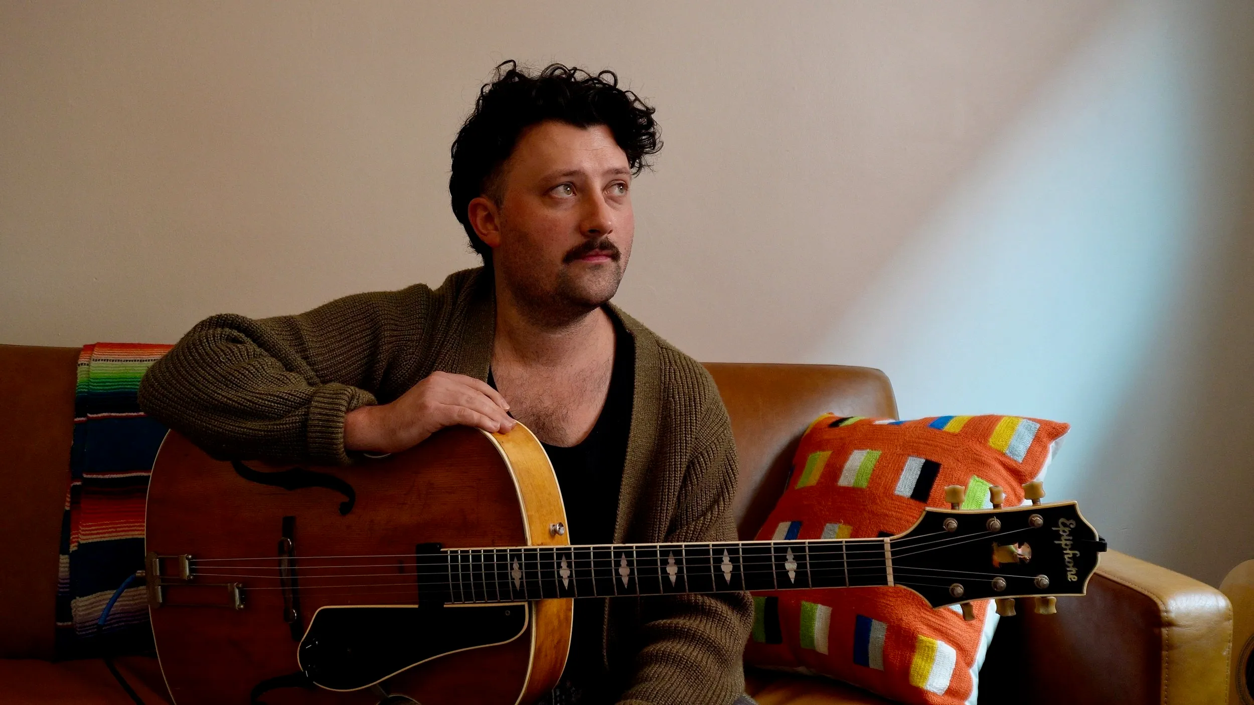 Musician Ronan Delisle seated with a guitar